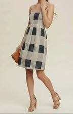 Woman wearing a checkered dress and straw hat on a beige background