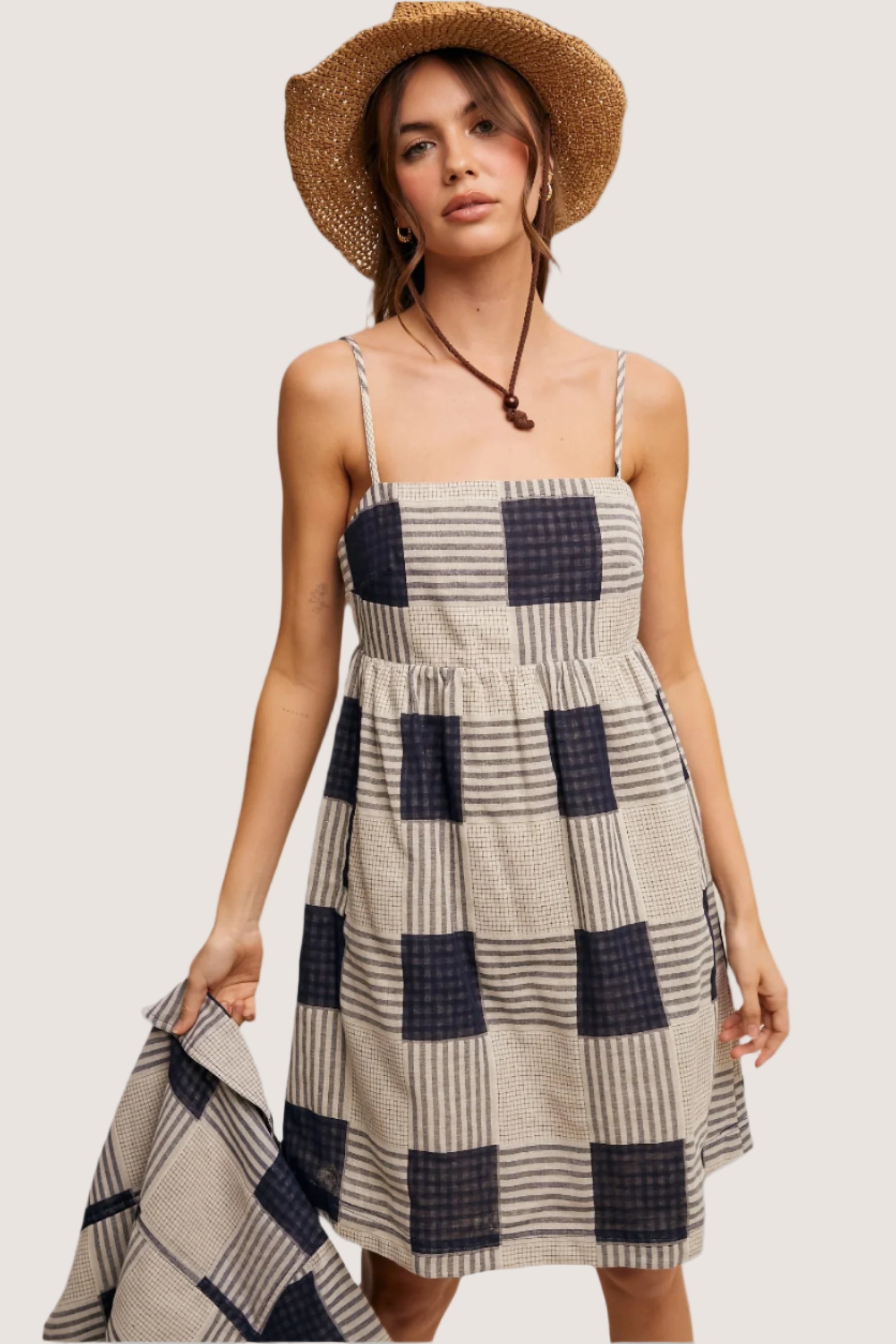 Woman wearing a checkered dress and straw hat on a beige background